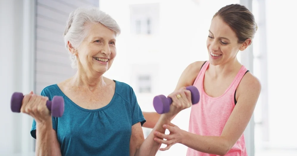 Senior woman, physiotherapist and weights in gym for fitness, wellness and arm injury recovery. Elderly client, physiotherapy and dumbbells in practice for exercise, muscle development and joint care