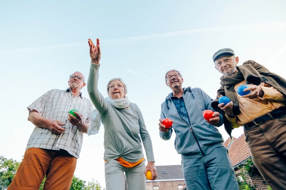Low-angle view of a group of elderly friends playing bocce outdoors, enjoying leisure time together