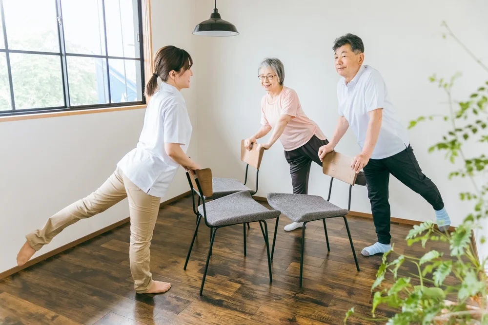 Seniors and elderly men and women doing chair exercises, exercise and rehabilitation at a nursing facility, and physical therapists, caregivers and trainers (legs)